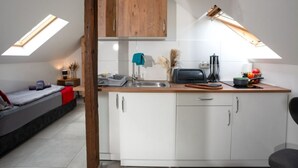 Een kleine keuken met witte kasten, een houten aanrecht en een dakraam.