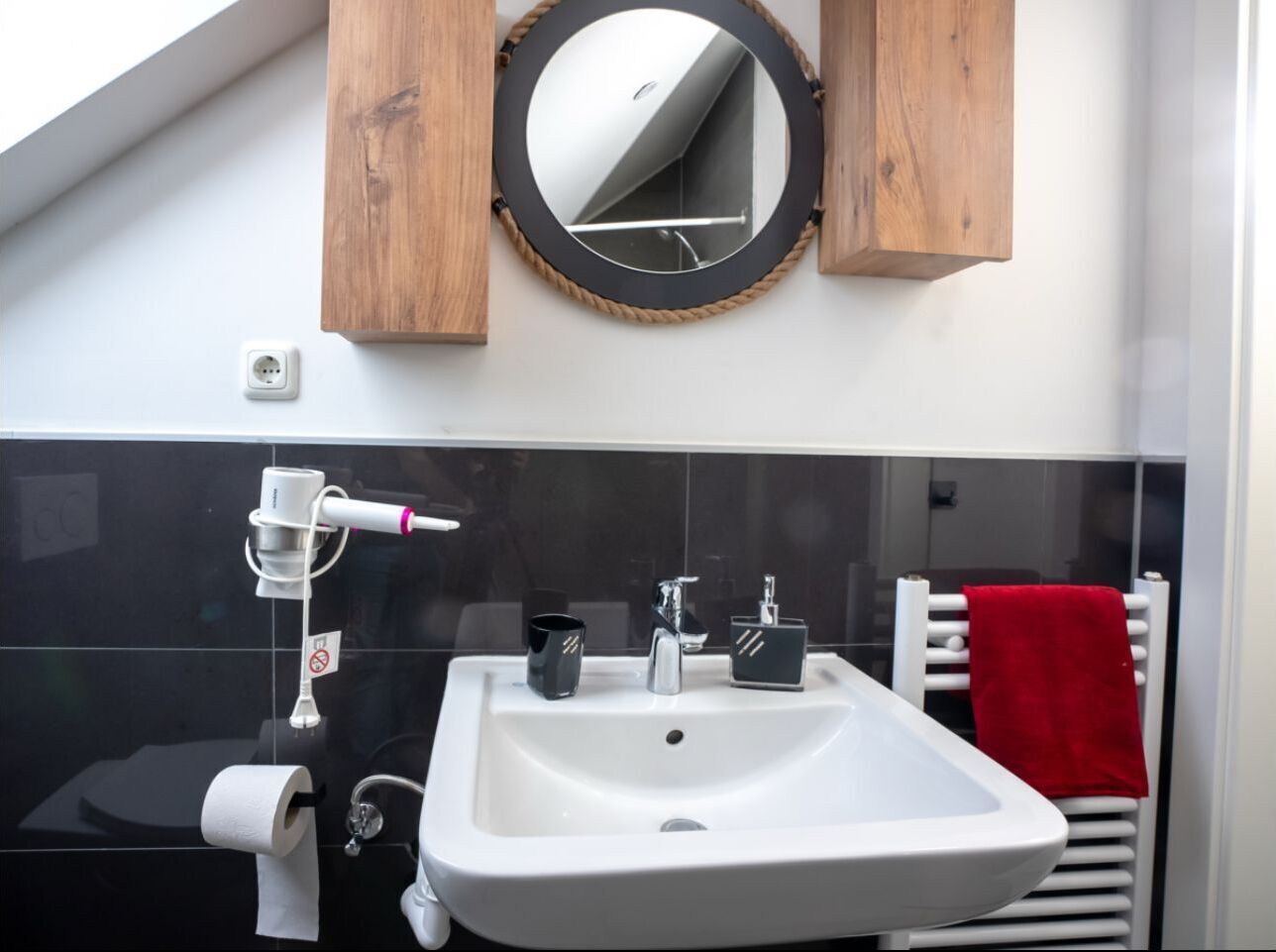 A bathroom with a white sink, a mirror, and a towel rack.