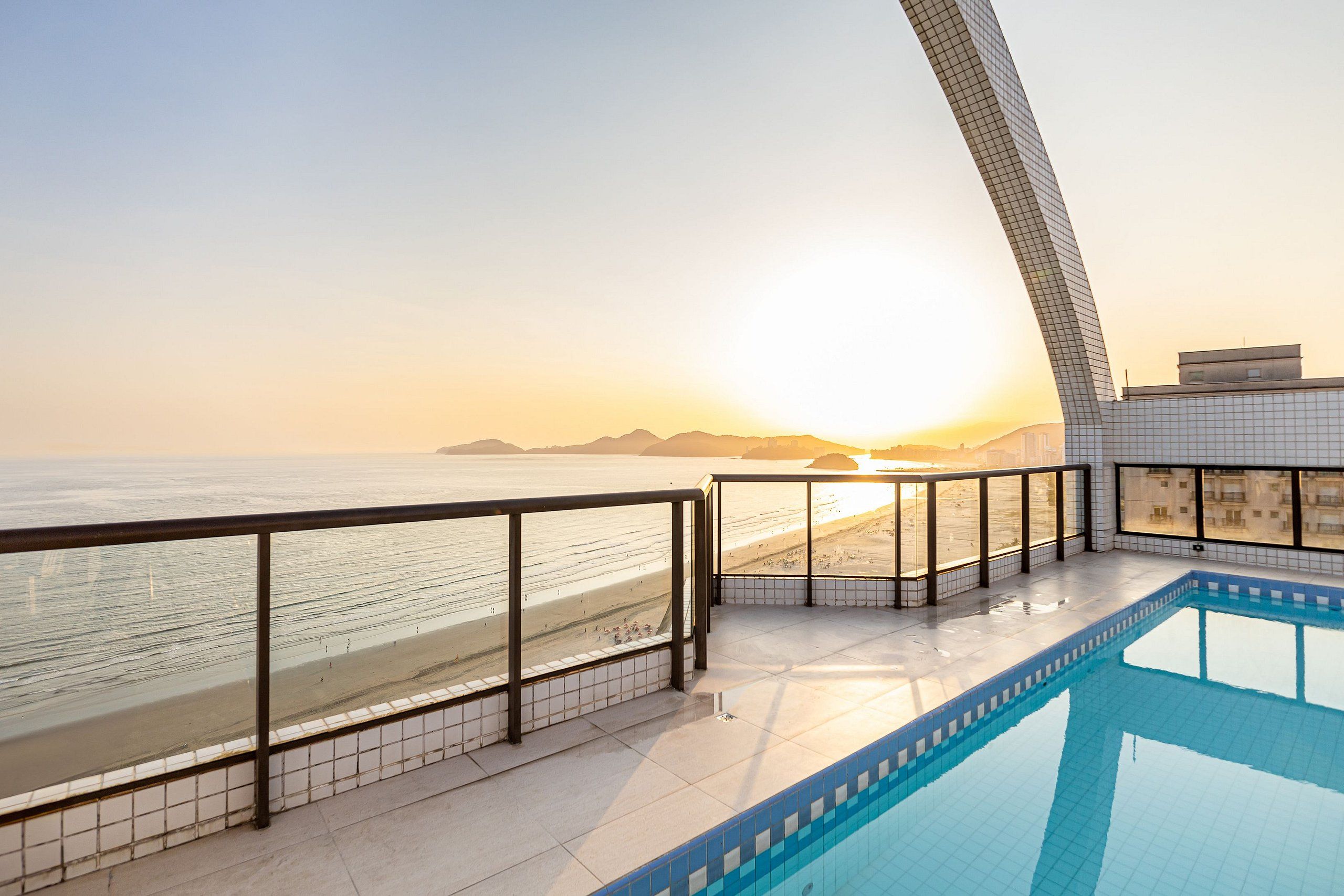 Una piscina con vista a la playa y al atardecer.