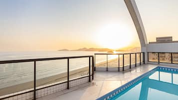 Una piscina con vista a la playa y al atardecer.