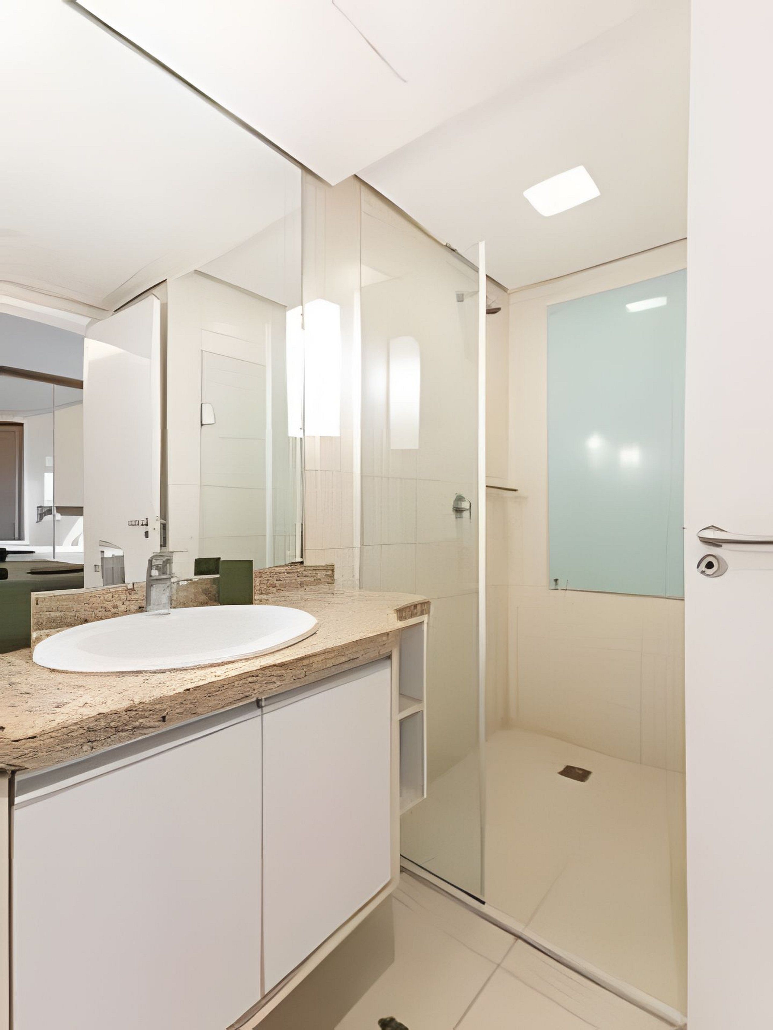 A modern bathroom with a glass shower enclosure, a white sink, and a large mirror.