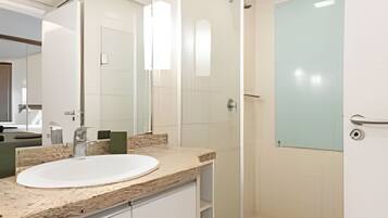 Un baño moderno con cabina de ducha de vidrio, un lavabo blanco y un espejo grande.