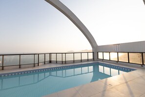 En swimmingpool med fri utsikt över havet och de avlägsna bergen.