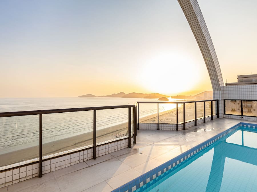 Una piscina con vista a la playa y al atardecer.