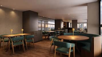 Un comedor moderno con mesas de madera y sillas tapizadas de verde, amplias ventanas con vista a la ciudad y una zona de cocina con vistas.