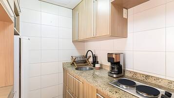 A compact kitchen with a sink, coffee maker, and two induction cooktops.
