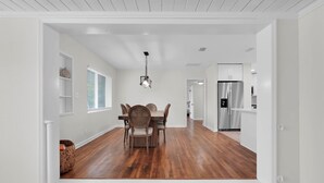 A modern kitchen with stainless steel appliances, a dining area with a wooden table and chairs, and a hallway leading to other rooms. - 3-bedroom House with Heated Pool in Delightful St. Augustine. Pet-Friendly! (St. Augustine)