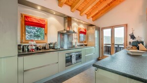 Una cocina moderna con una isla grande, hornos dobles y vistas al exterior.