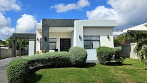 A modern two-story house with a flat roof, a covered patio, and a well-maintained lawn. - Beautiful 3BR villa in Ocho Rios near Dunn's River falls, gorg beaches plus more (Ocho Rios)