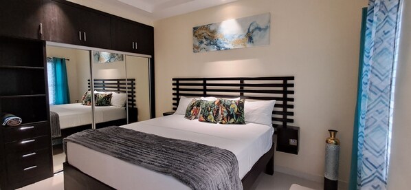 A bedroom with a bed, a wardrobe, a nightstand, a decorative vase, and a painting on the wall.