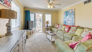 A living room with a sofa, a coffee table, a TV, and a ceiling fan. - Steps to Beach: NMB Condo w/ Balcony & Pool Access (North Myrtle Beach)