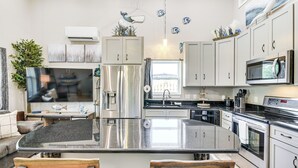 Cozinha moderna com eletrodomésticos de aço inoxidável, uma ilha central e armários brancos.