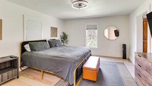 Un dormitorio moderno con cama, mesita de noche, banco y cómoda.