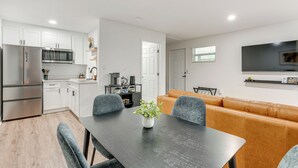A modern kitchen with white cabinets, a built-in microwave, and a dining area with a dark table and grey chairs. - WFH Friendly! Stylish Lakeland Studio (Lakeland)