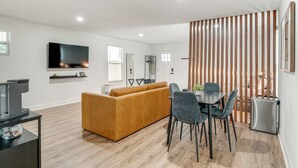 A modern living room with a sofa, dining table, chairs, a TV, and a kitchen area with a refrigerator. - WFH Friendly! Stylish Lakeland Studio (Lakeland)