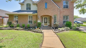 A two-story brick house with a front entrance, a covered porch, and a well-maintained lawn.