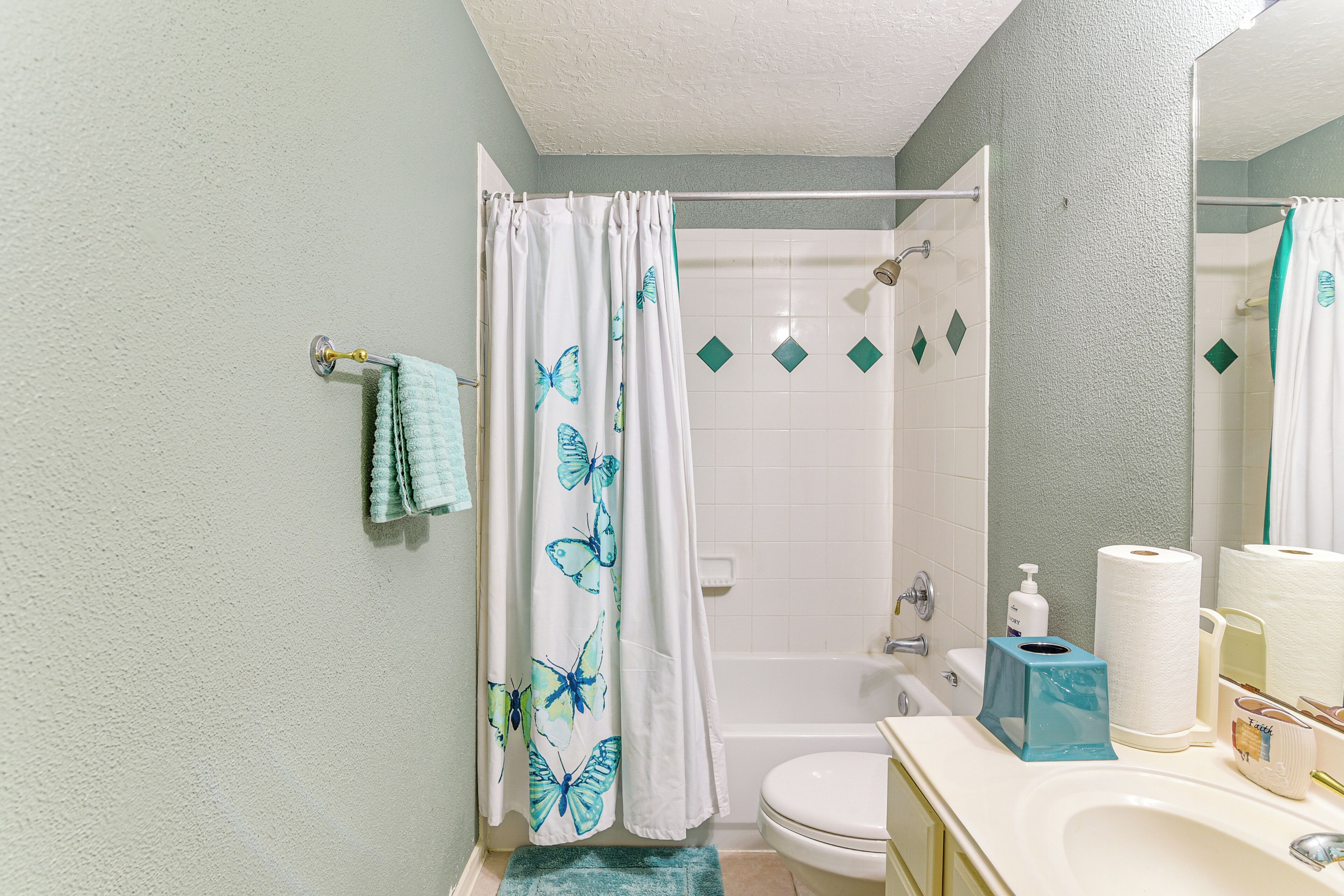 Un baño con cortina de ducha, inodoro, lavabo y espejo.