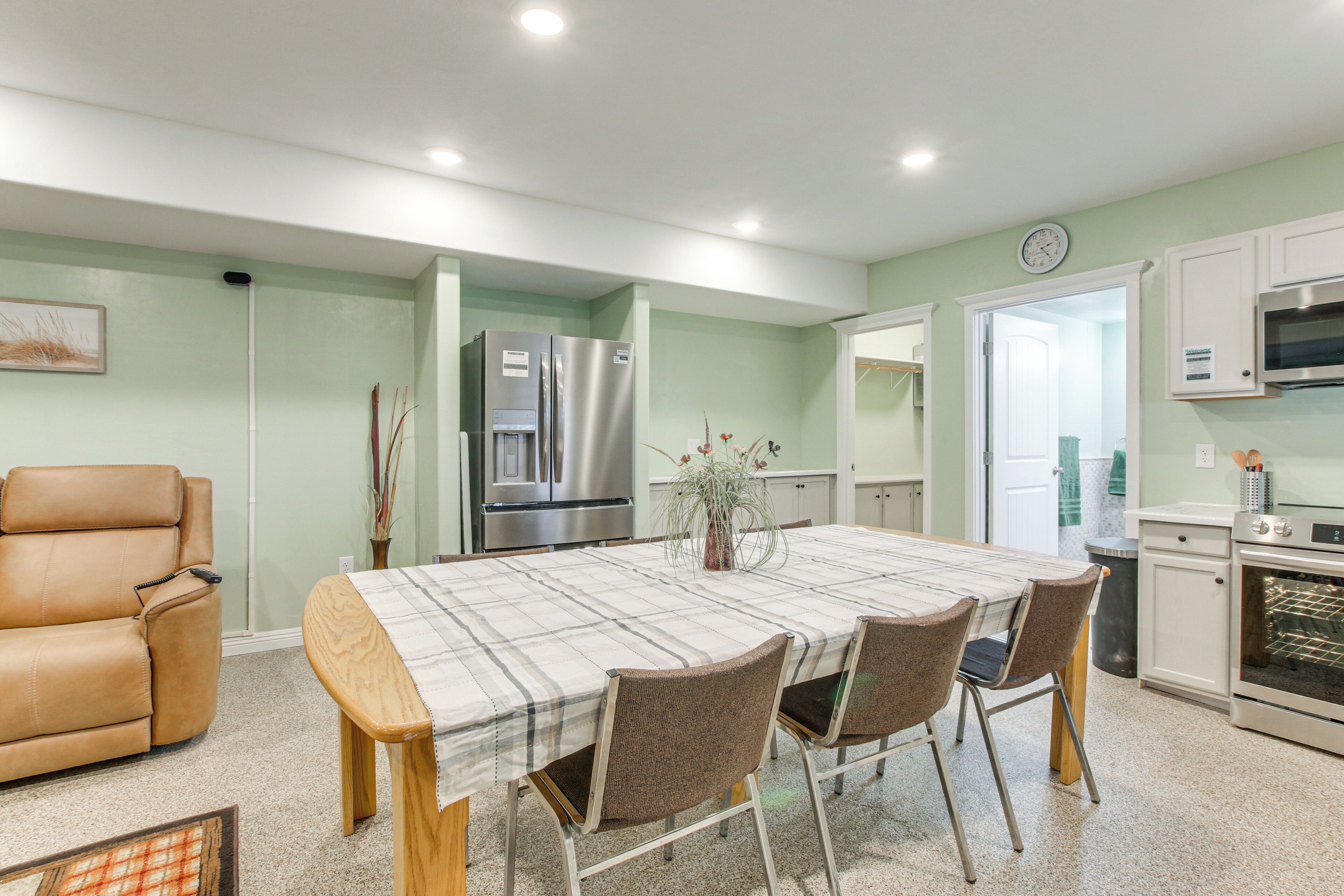 A modern kitchen with a dining area, featuring a stainless steel refrigerator, oven, and microwave.