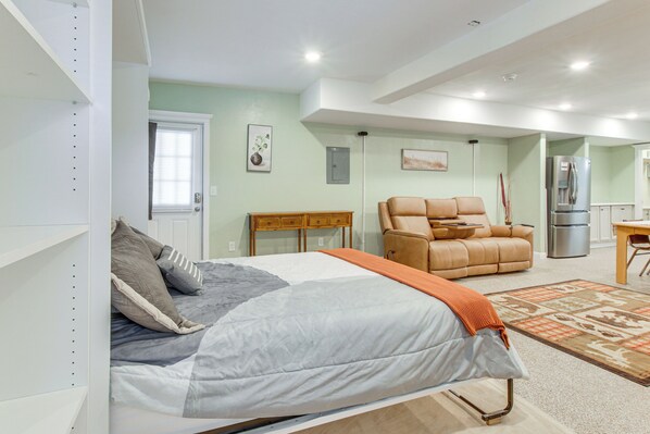 A bedroom with a bed, a sofa, a desk, and a refrigerator.