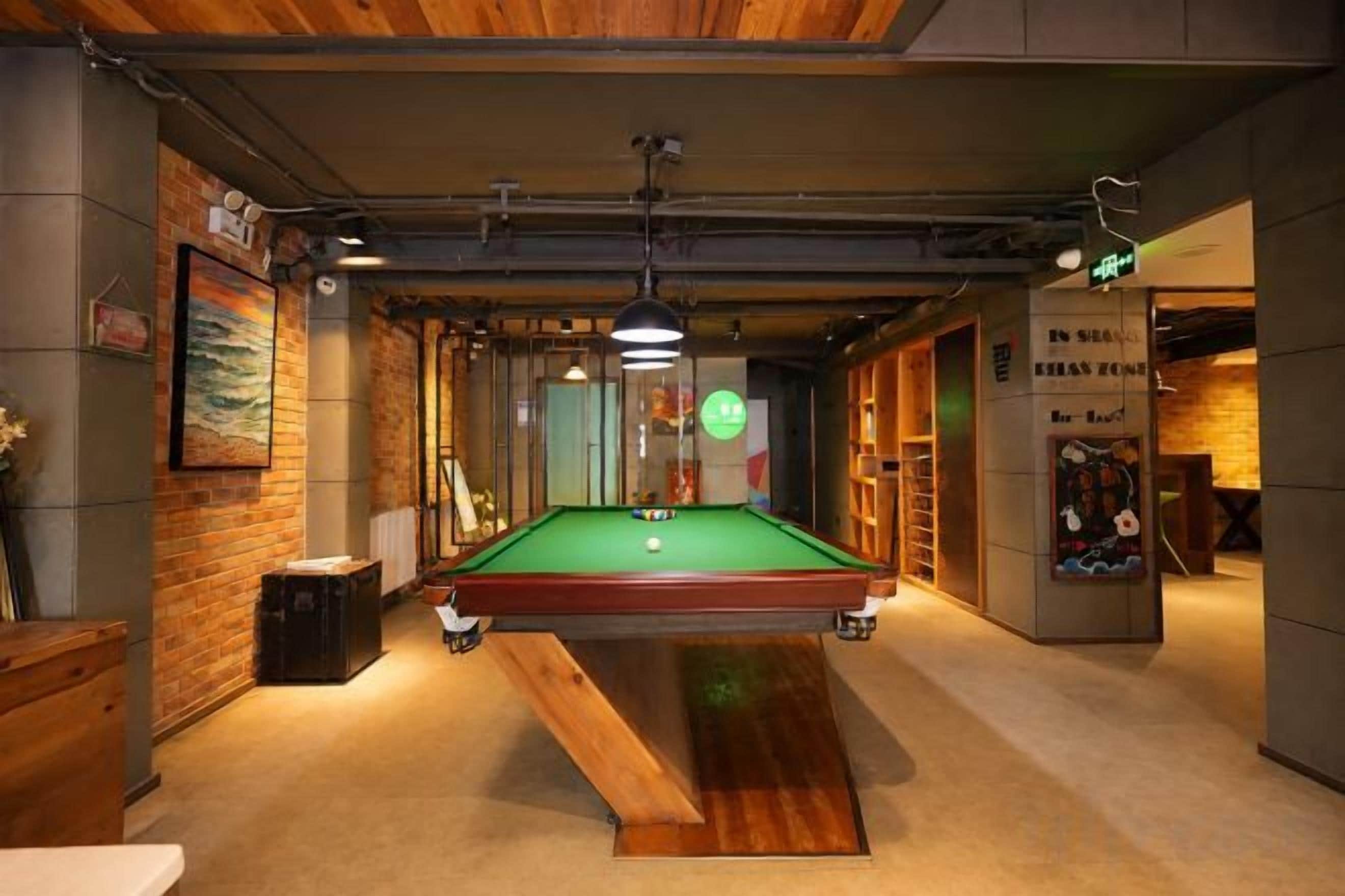 Une table de billard dans une pièce aux murs en bois et où se trouve un banc.
