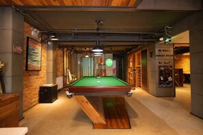 A pool table in a room with wooden walls and a bench. - In Hotels (Qingdao)