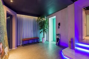A hallway with a bench, a potted plant, and a staircase with illuminated steps. - In Hotels (Qingdao)