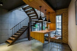 Un interior moderno con una zona de bar de madera, una escalera y vistas al exterior.