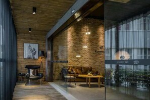 A modern hotel lobby with a brick wall, wooden ceiling, and a seating area with a table and chairs. - In Hotels (Qingdao)