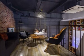 A cozy lounge area with a hanging light fixture, a sofa, a chair, and a small table.