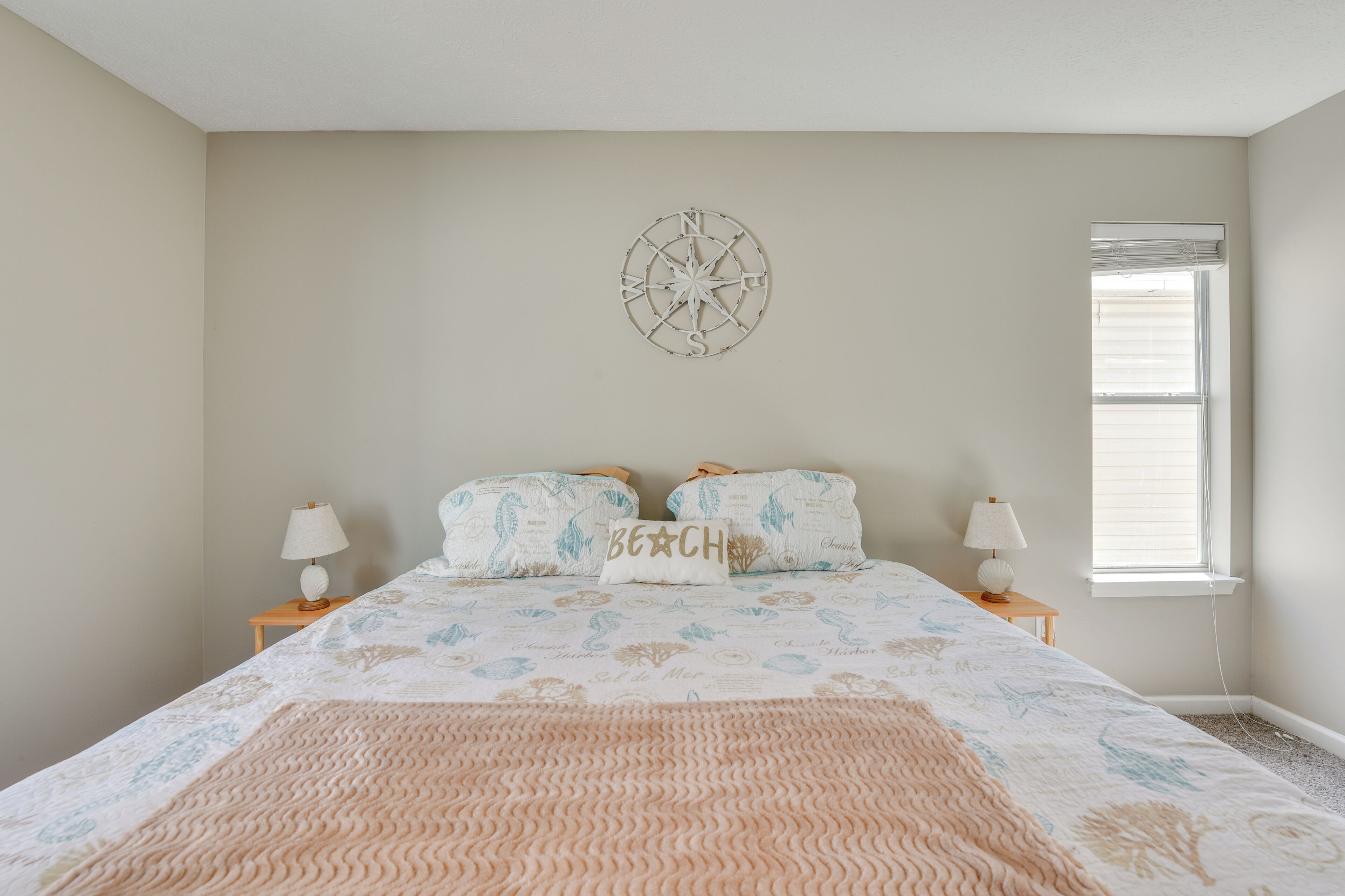 Un dormitorio con una cama, dos mesitas de noche, un reloj de pared y una ventana.