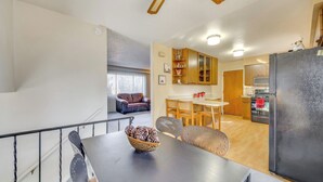A modern kitchen with a dining area, wooden cabinets, and a black refrigerator. - 2 Mi to Citadel Mall: Home w/ Furnished Patio! (Colorado Springs)