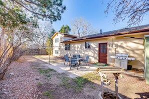 Une maison avec un patio, un barbecue et un abri de jardin.