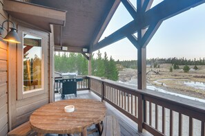 Une terrasse en bois avec une table et des chaises, un barbecue et une vue sur un paysage naturel.