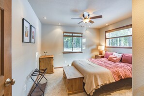 Une chambre à coucher avec un lit, un ventilateur de plafond, une fenêtre, une table de chevet et une lampe.