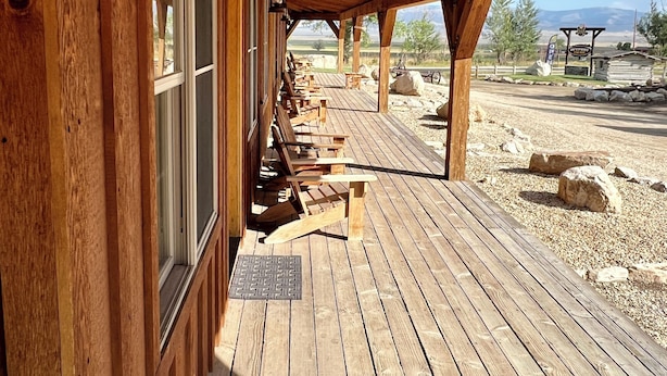 A wooden deck with benches, a lantern, and a view of a rural landscape. - Cabin 10 Deluxe Lrg 2 Story at the Almo Inn near City of Rocks/Castle Rock Idaho (Almo)