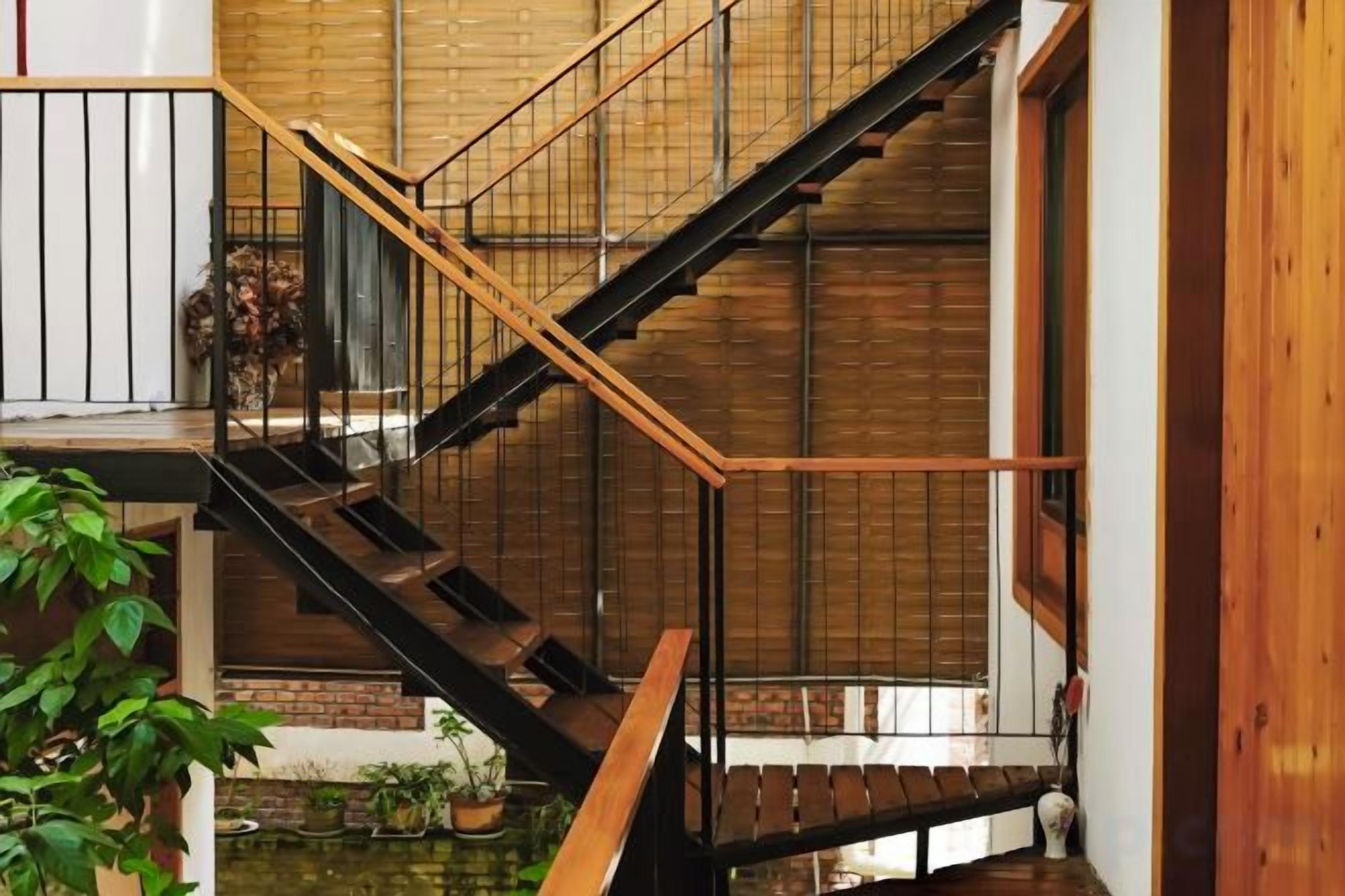 A multi-level interior with a staircase, wooden railings, and a small water feature.