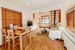 A living room with a wooden dining table, chairs, a sofa, and a TV.