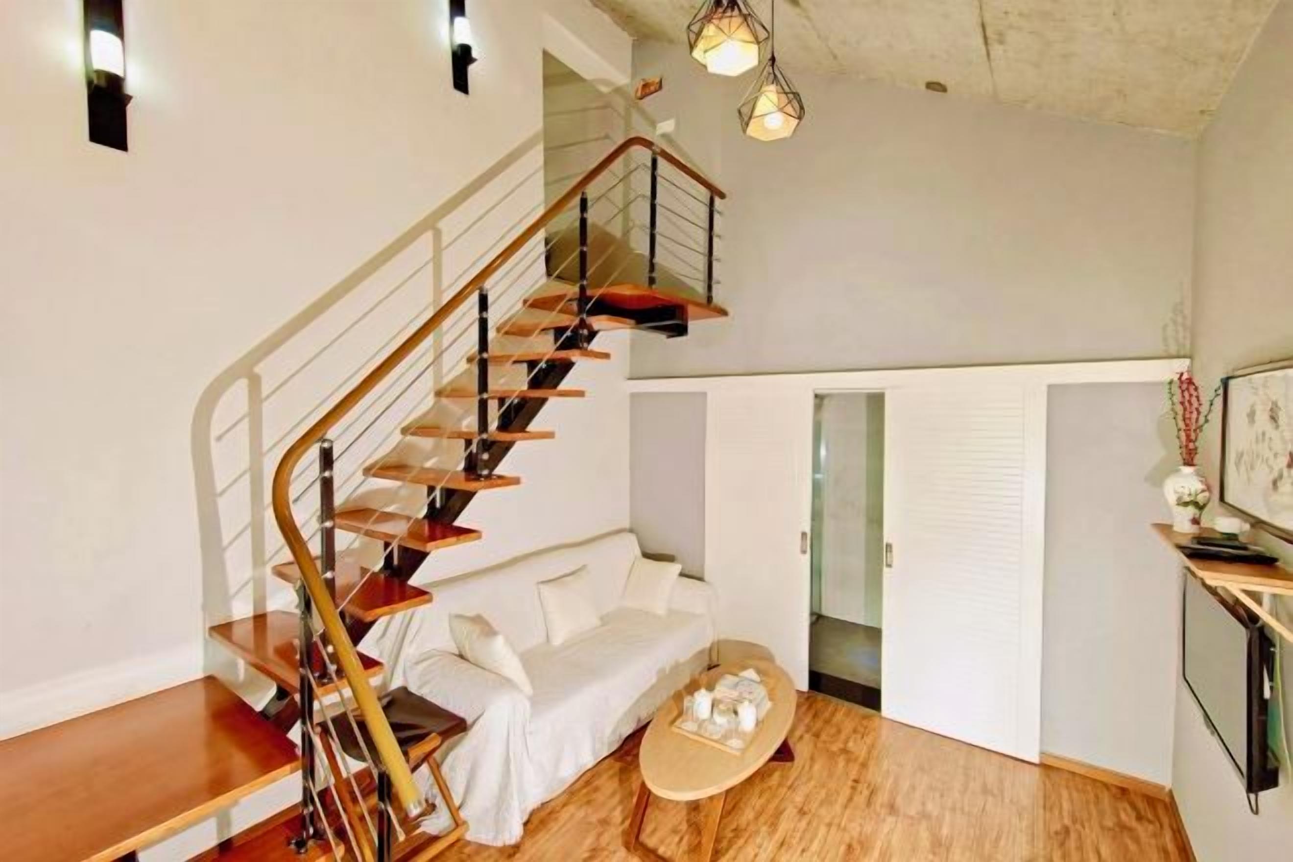A modern interior with a wooden staircase, a white sofa, and a coffee table.