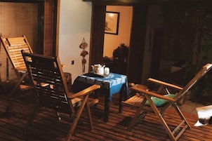 Una habitación con suelo de madera, una mesa con mantel azul y dos sillas de madera.