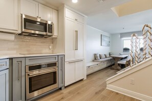 Una cocina moderna con electrodomésticos de acero inoxidable, armarios blancos y piso de madera.