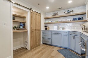 Una cocina con armarios azul claro, estantes de madera y una puerta corrediza tipo granero.