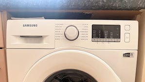 A Samsung front-loading washing machine with a digital control panel, energy efficiency rating, and a transparent door. - Lovely apartment with WiFi in charming Stretford (Stretford)