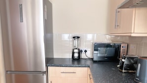 A modern kitchen with stainless steel appliances, a built-in microwave, and a black induction cooktop. - Lovely apartment with WiFi in charming Stretford (Stretford)