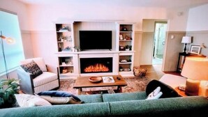 Ein Wohnzimmer mit Kamin, Fernseher und einer Couch.