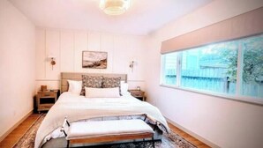 Ein Schlafzimmer mit Bett, Nachttischen, Fenster mit Blick und einem Bild an der Wand.