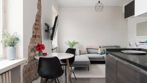Eine moderne Küche mit Essbereich, ausgestattet mit einer Ziegelwand, einem runden Tisch mit Stühlen, einer Couch und einer kleinen Pflanze.