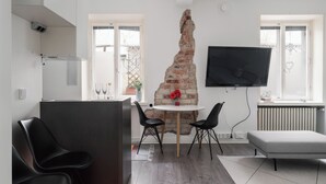 Eine moderne Küche mit Backsteinwand, einem runden Tisch mit Stühlen, einem Flachbildfernseher und einem Essbereich.