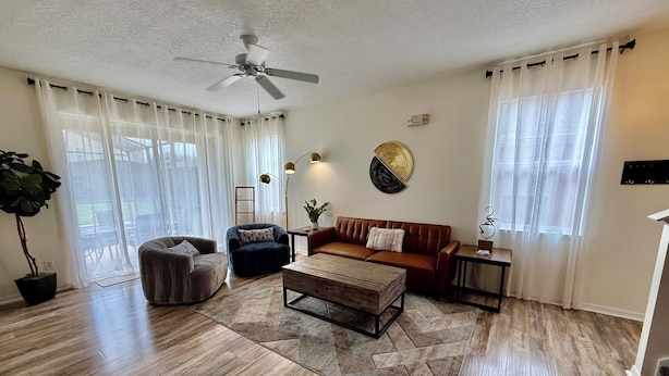 A living room with a ceiling fan, a brown leather sofa, a dark blue armchair, a wooden coffee table, and a potted plant. - Disconnect to Reconnect! (Davenport)