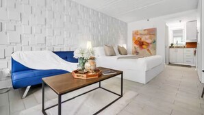 A modern living room with a blue sofa, white couch, and a coffee table with decorative items. - Luxury suite pool & gym. 8 mins from Disney park (Kissimmee)