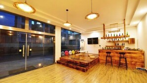 A modern interior with a wooden bar area, large windows, and pendant lighting. - Moment Inn (Huangshan City)